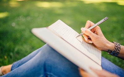 Frau schreibt in ein Notizbuch im Park