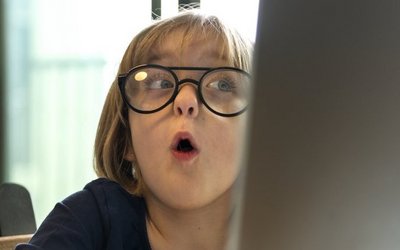 Ein Mädchen arbeitet am PC und hat einen überrascht geöffneten Mund